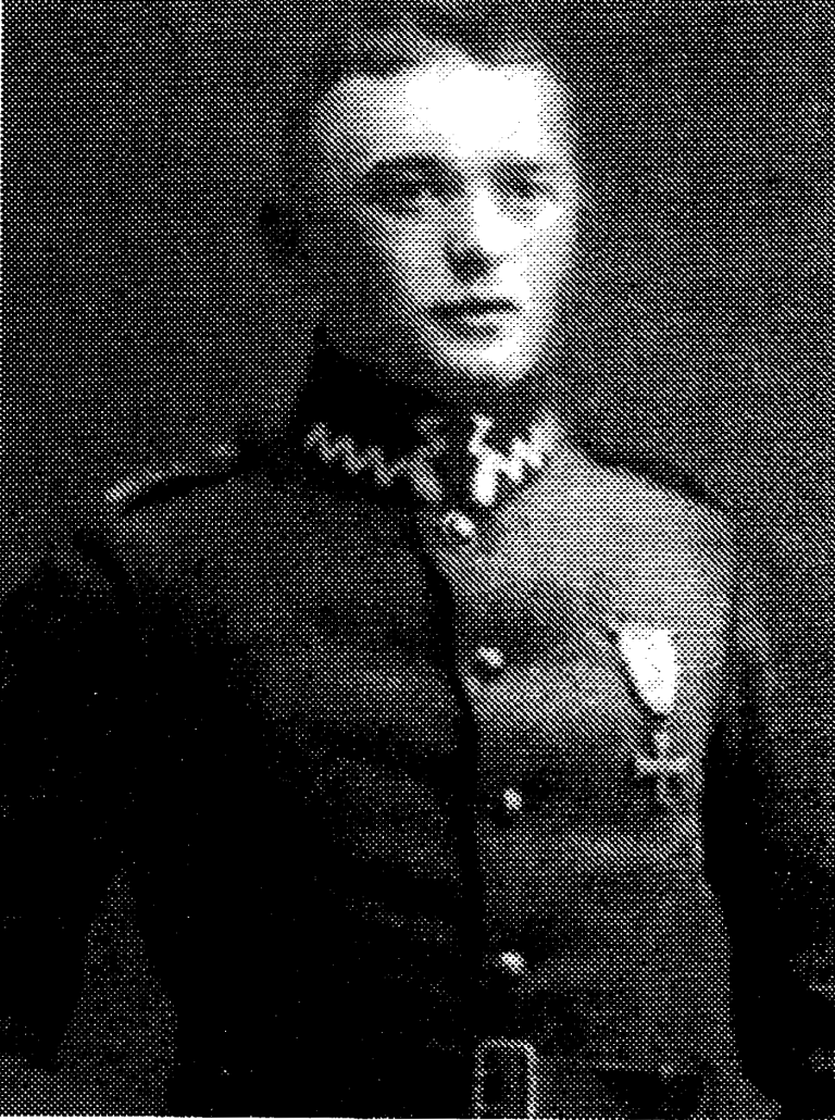 Ziarnisty czarno-biały portret Andrzeja Bretta w mundurze powstańczym; mężczyzna stoi z odznaką na piersi i krzyżem na kołnierzu.