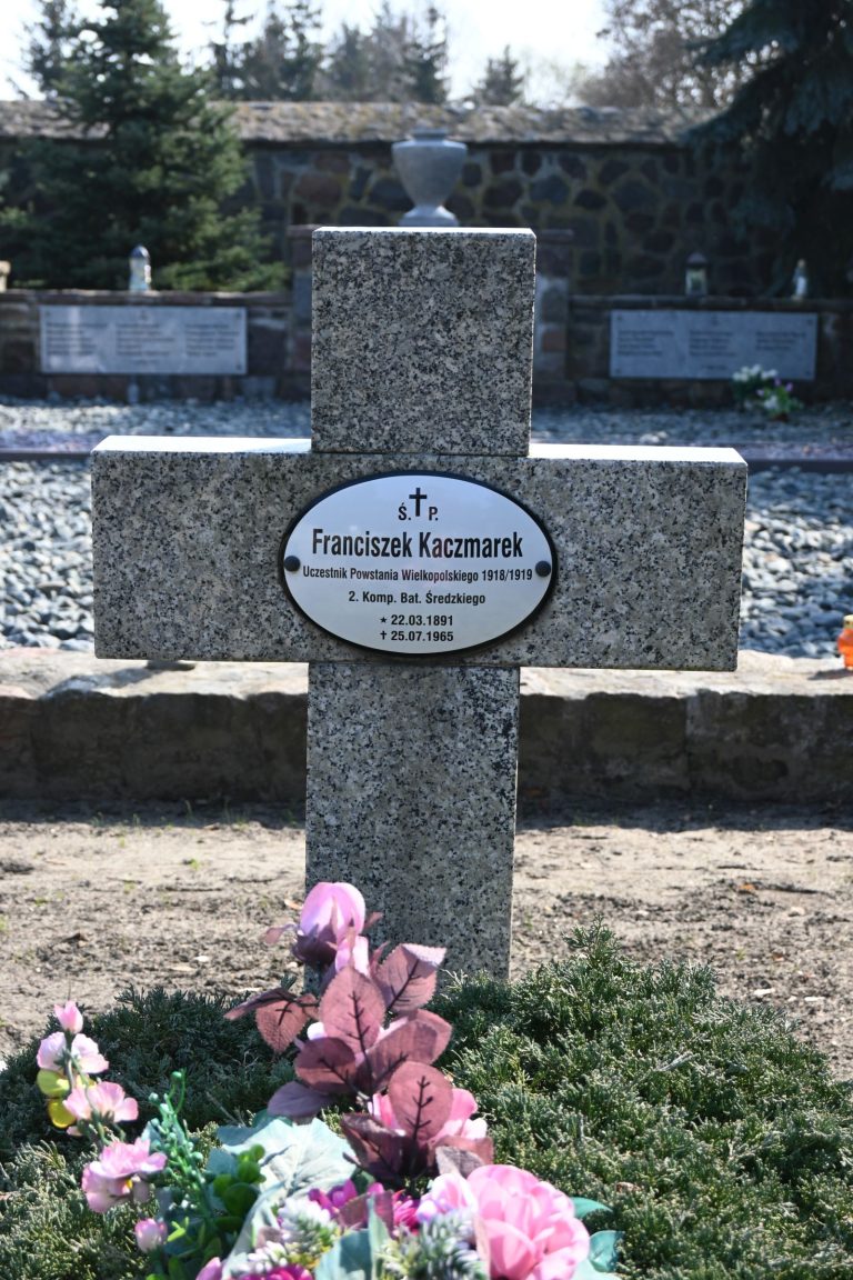 Krzyż z tabliczką imienia i nazwiska powstańca Franciszka Kaczmarka ozdobiony kwiatami na kwaterze powstańców w Środzie Wielkopolskiej.