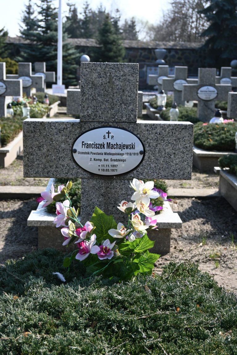 Krzyż z tabliczką imienia i nazwiska powstańca Franciszka Machajewskiego ozdobiony kwiatami na kwaterze powstańców w Środzie Wielkopolskiej.