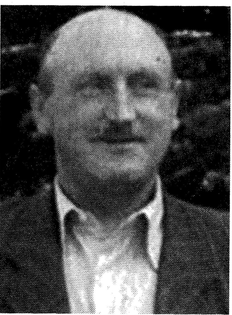 Ziarnisty czarno-biały portret Jana Kaczora, powstańca wielkopolskiego; mężczyzna z wąsem w marynarce na tle roślin.