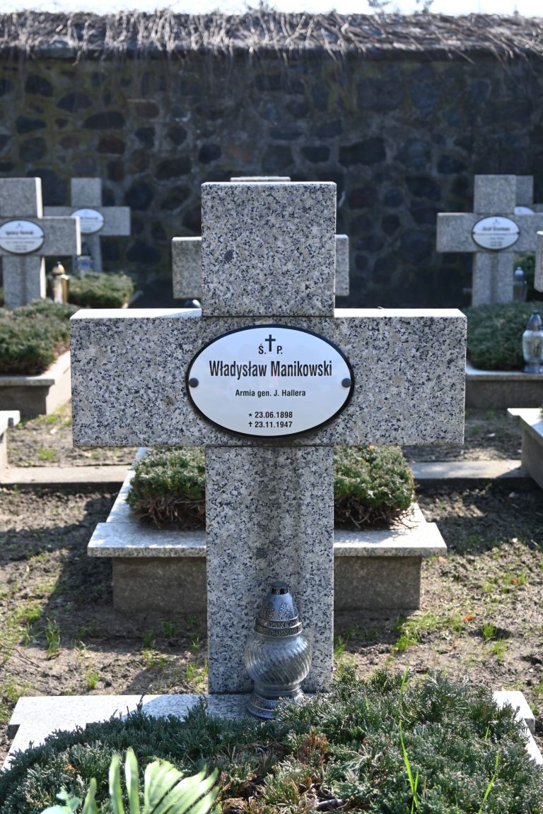 Nagrobek Władysława Manikowskiego w Kwaterze Powstańców Wielkopolskich – kamienny krzyż z owalną tabliczką z imieniem i zniczem u podstawy